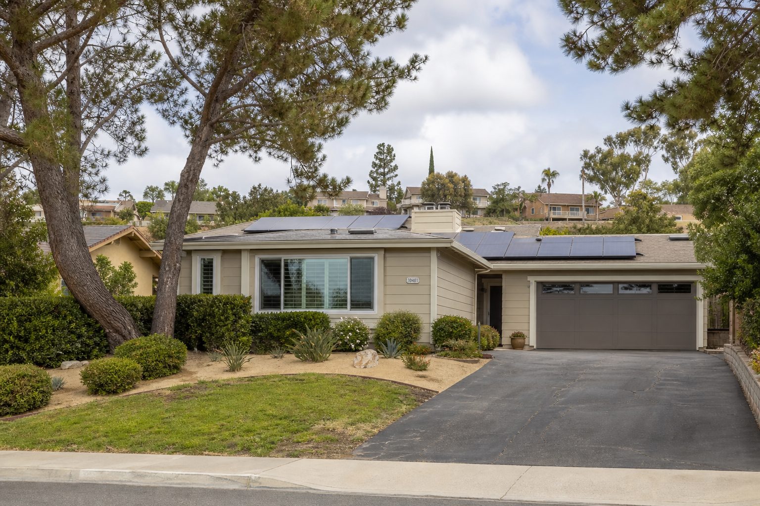Contemporary three-bedroom home with solar panels and mature trees on a residential lot in Mira Mesa, San Diego neighborhood.