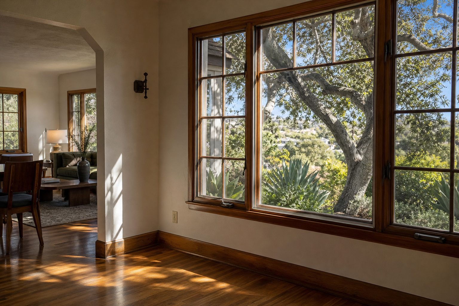 Light-filled 1950s ranch home interior with original wood trim and view of mature landscaping in North Park, San Diego.