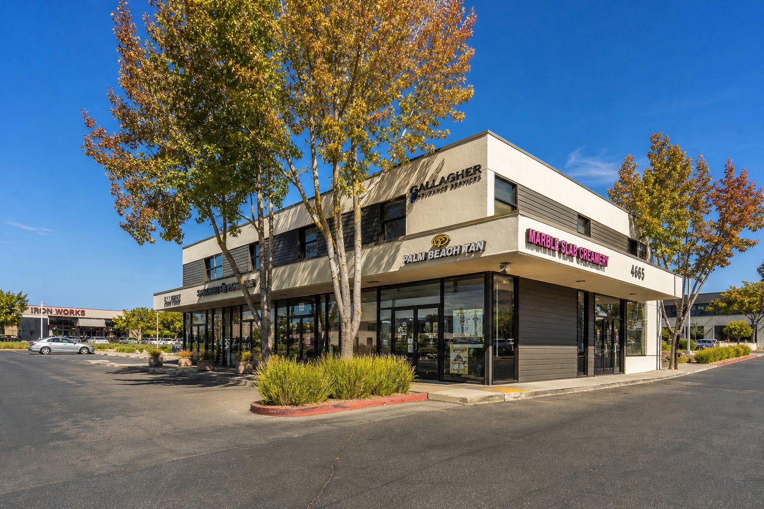 Multi-tenant retail strip center with two-story mixed-use space, mature trees, and parking lot in Kearny Mesa near Convoy Street corridor.