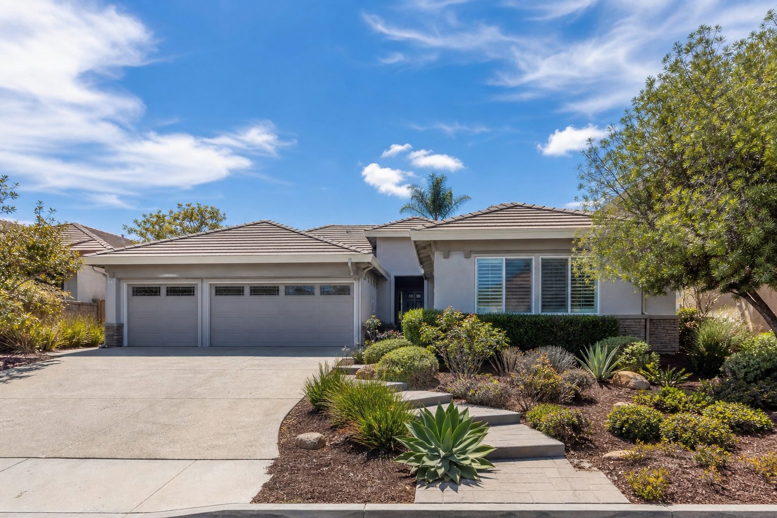 Contemporary single-story home with mature desert landscaping and three-car garage in Eastlake Otay Ranch community, Chula Vista.