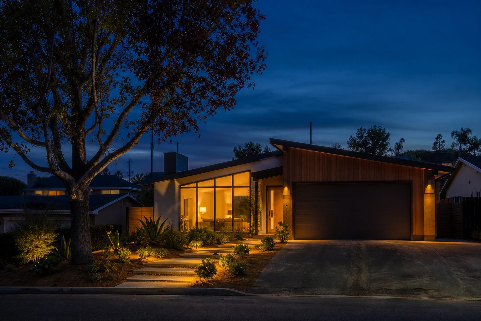 Renovated Clairemont home at twilight with warm interior glow and landscape lighting on the front entry.