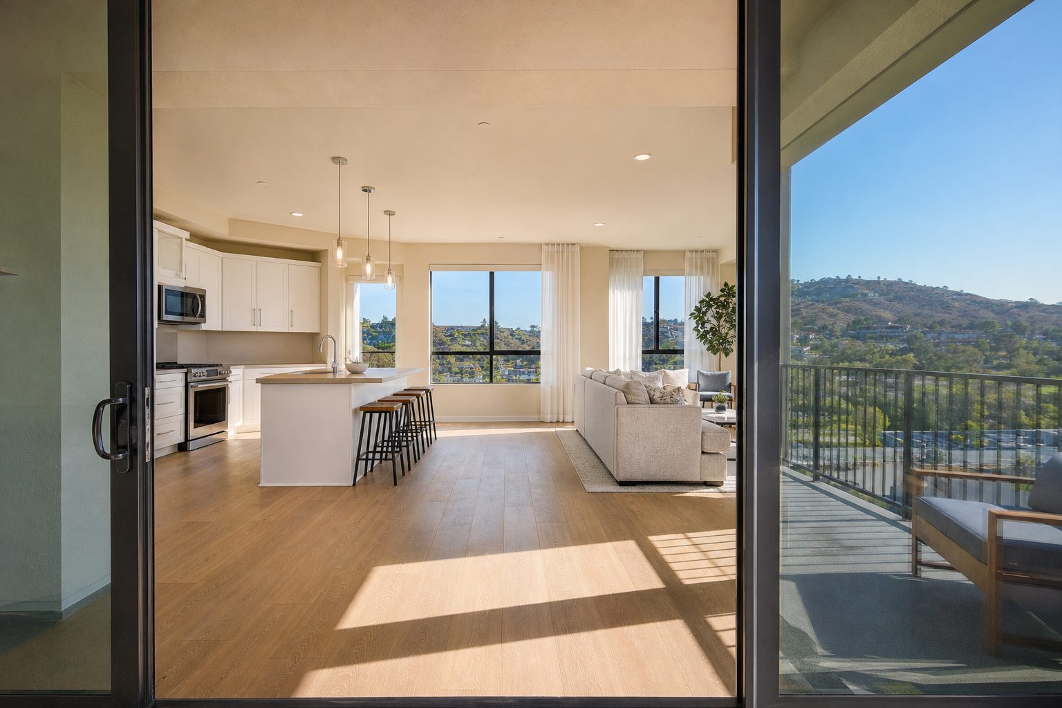 Open-concept Mission Valley condo interior with kitchen, living room, and valley view through sliding glass doors.