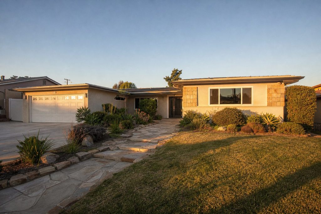 Mid-century ranch home on large Clairemont lot with mature landscaping and warm afternoon sunlight.